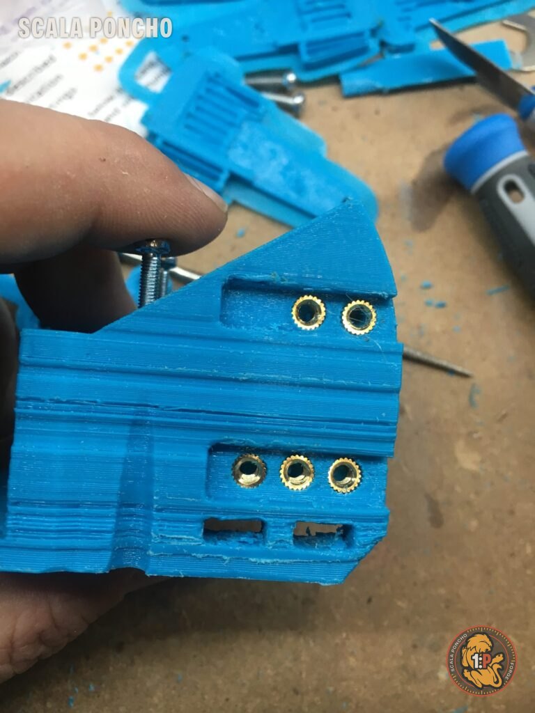 Pezzo azzurro stampato in 3D con inserti filettati in ottone nei fori
