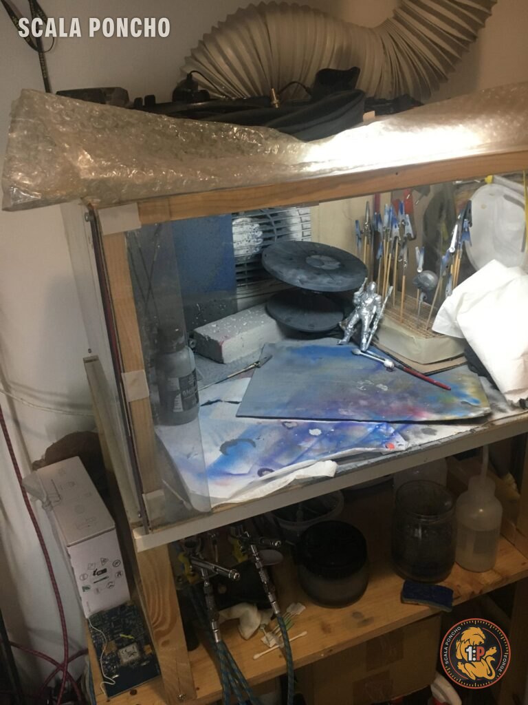 Cabina di verniciatura vista di lato con il tubo flessibile di scarico in alto e una miniatura appena verniciata all'interno
