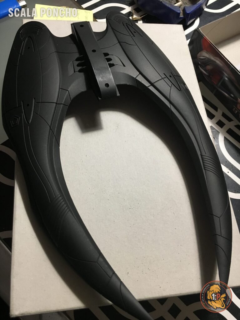 Scafo a mezzaluna del Cylon Raider in plastica nera appoggiato su un cartone