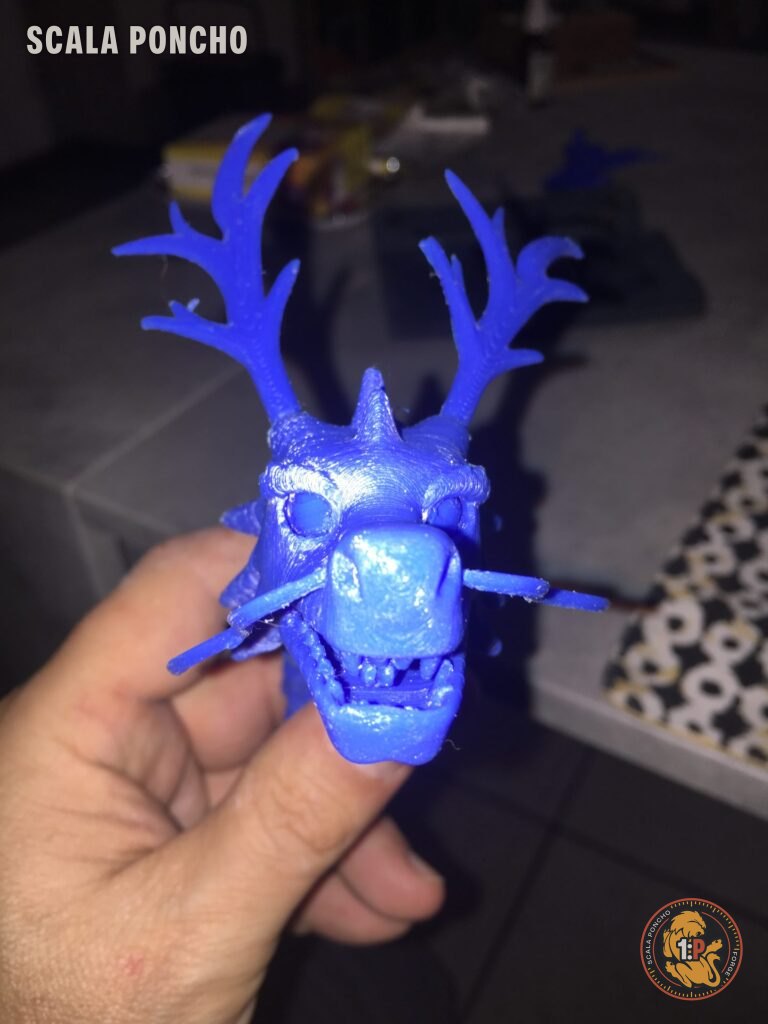 Testa di drago con corna stampata in filamento blu tenuta in mano