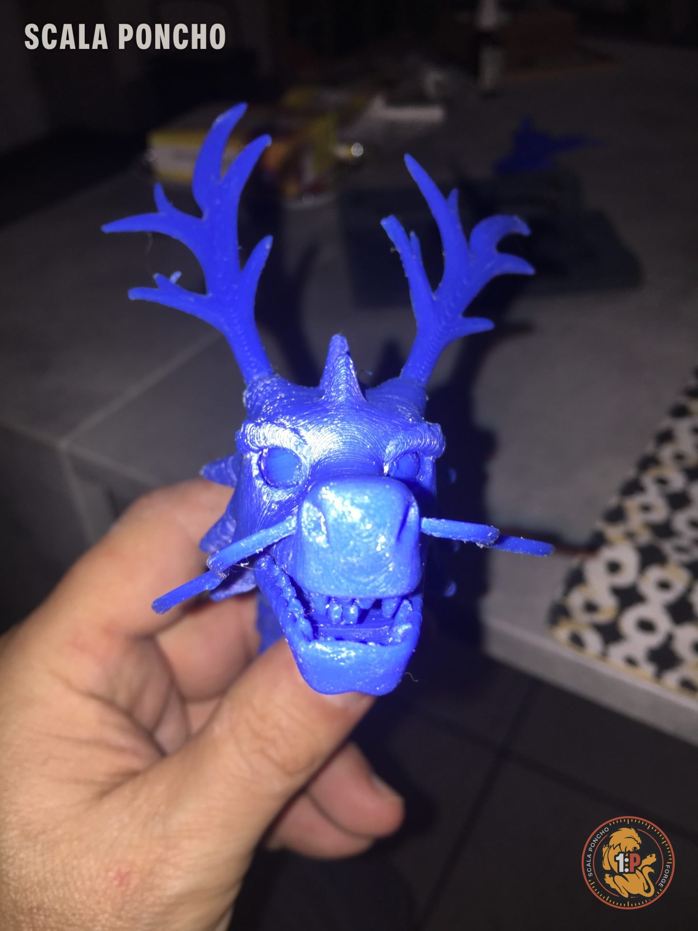 Testa di drago con corna stampata in filamento blu tenuta in mano