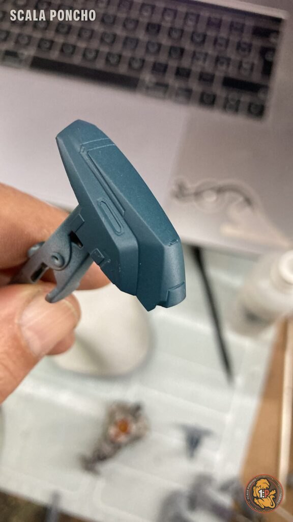 Pezzo della corazza del Gipsy Avenger verniciato blu metallizzato tenuto con una pinzetta