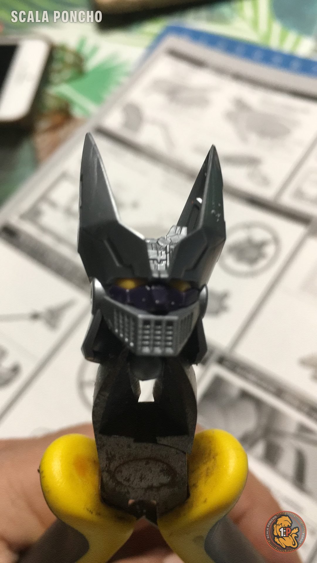 Testa del Grande Mazinger in montaggio tenuta con delle pinze gialle sopra le istruzioni