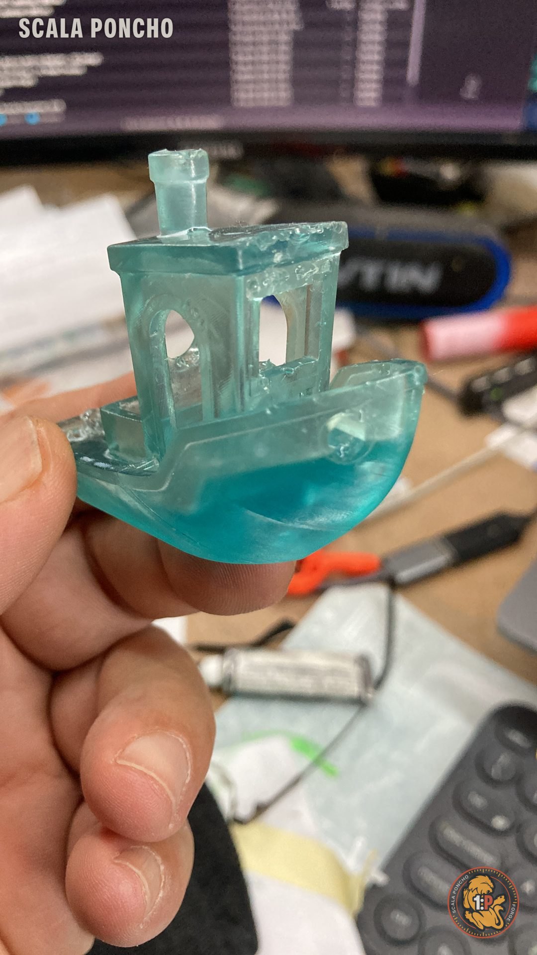 Benchy printed in clear aqua resin held between the fingers