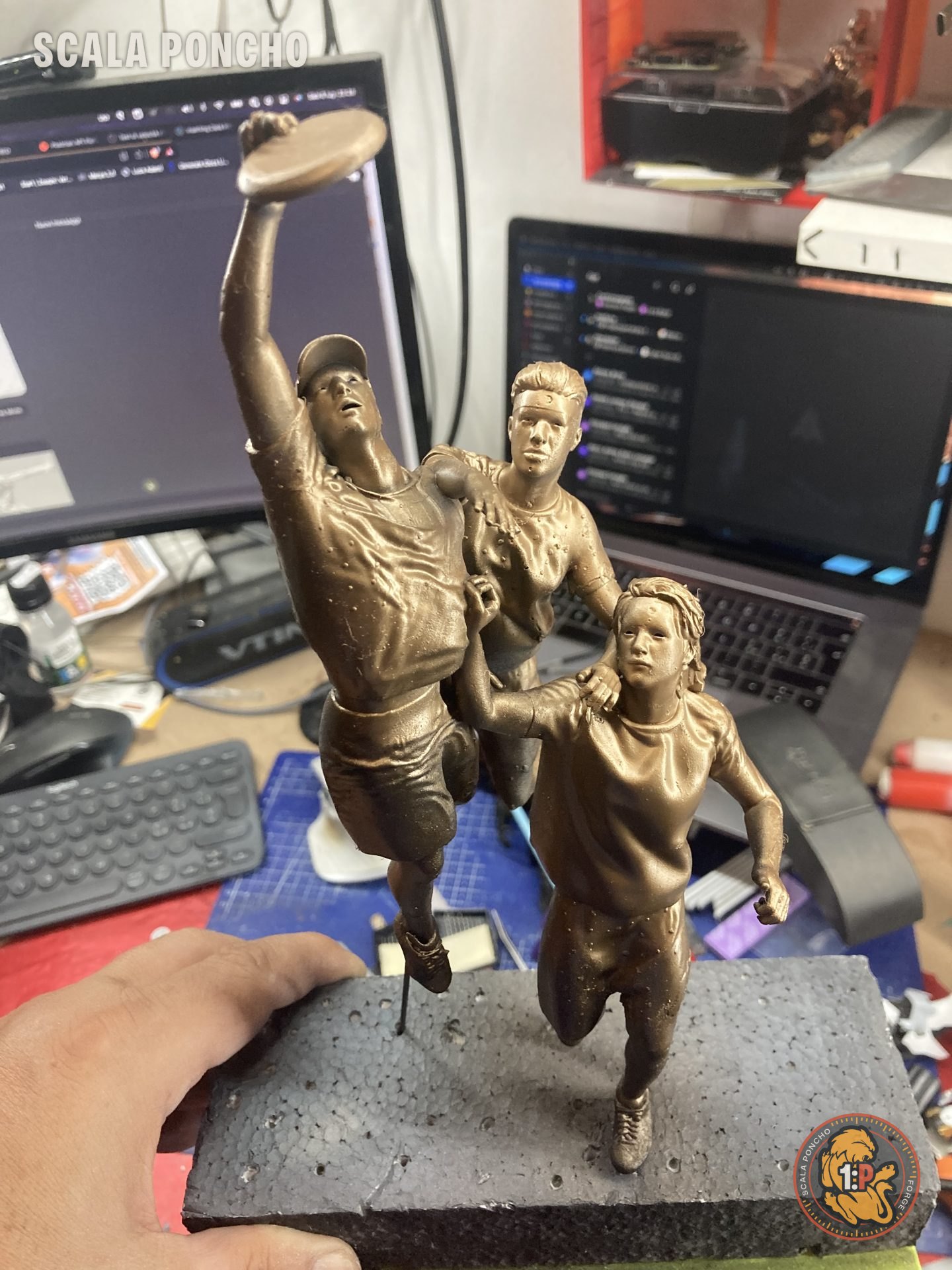Statua di giocatori di frisbee dipinta color bronzo su una base scura