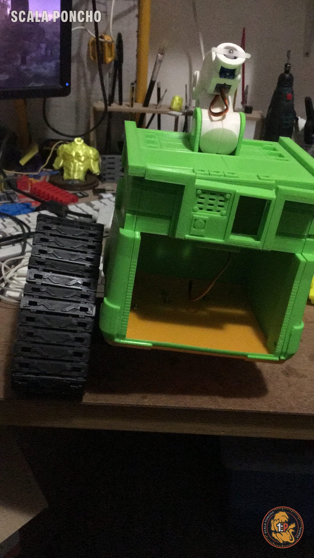 WALL-E verde con la testa smontata e i cavi dell'elettronica in vista sul banco